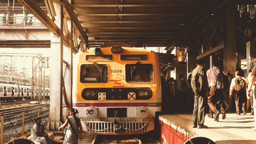 A train approaching a railway station with a bustling platform