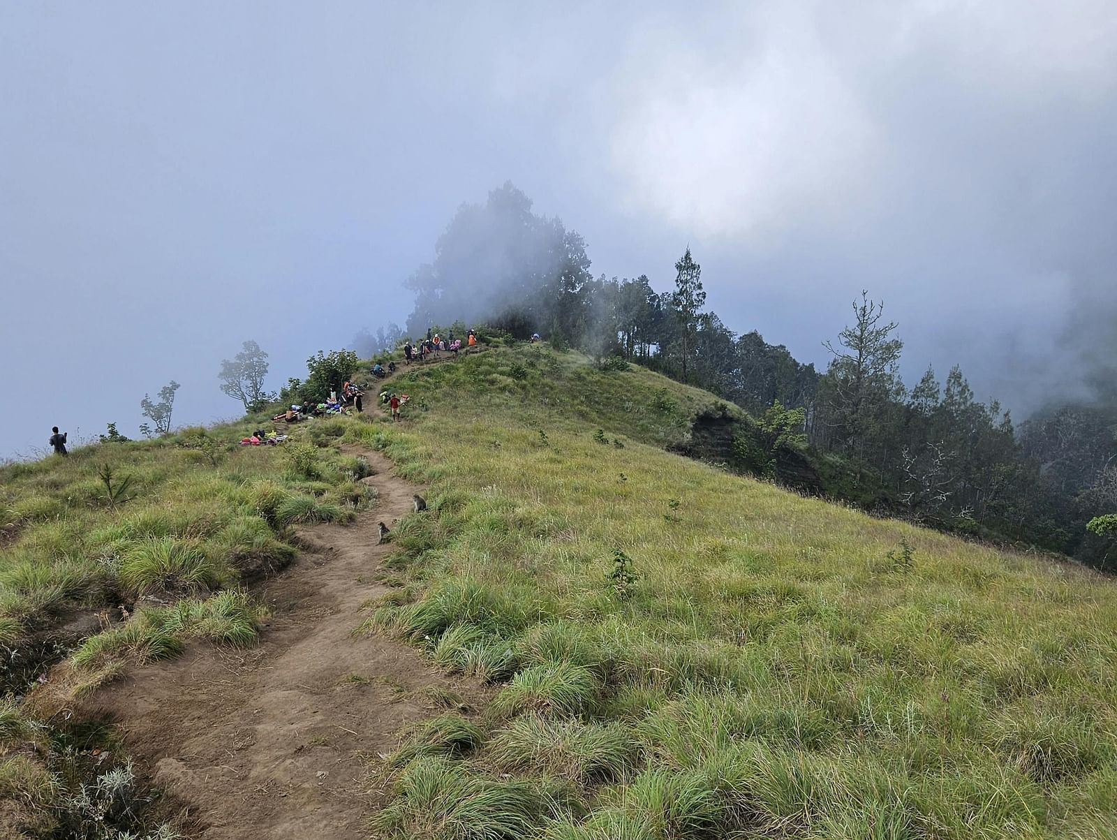 An image road trail on a mountain top with clouds in the background