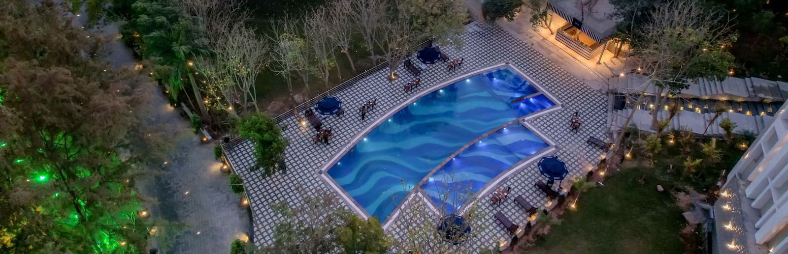 Aerial view of a swimming pool surroudned by trees at Essentia Luxury Resort and Spa, Udaipur