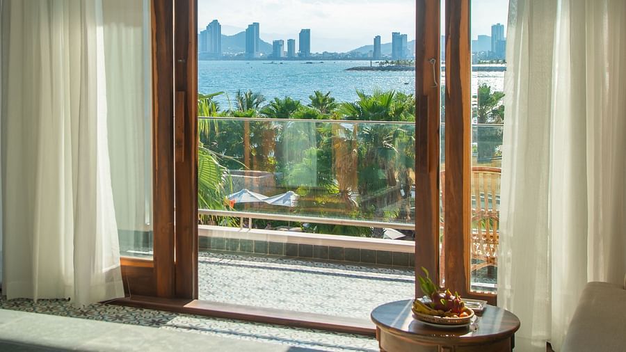 Step onto the balcony through glass doors framed in elegant wood, opening up to a breathtaking view that captivates the senses - Alibu Resort Nha Trang