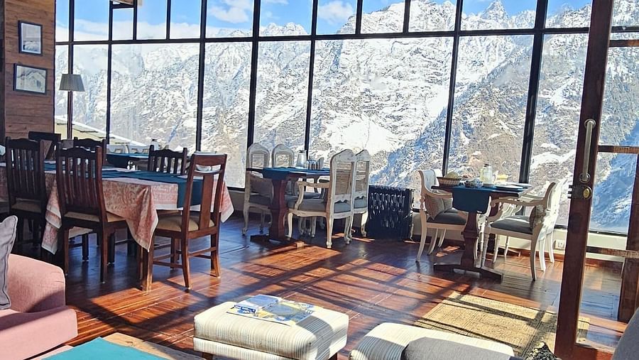 Image of dining area with tables and chiars with views of the mountains | Faraway Cottages, Auli