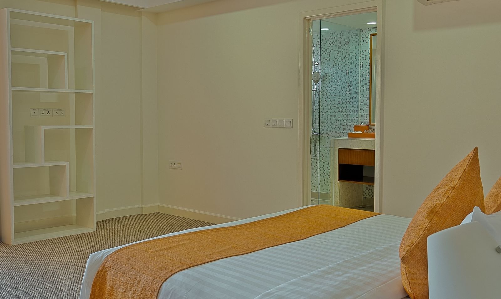 A hotel bedroom with a white bed, orange accents, and a mirrored closet door | Penthouse | Central Mansions, Phnom Penh