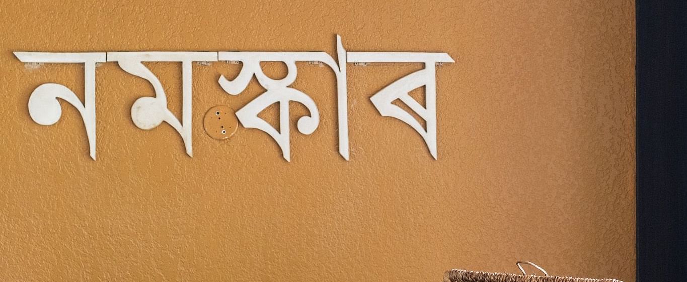Reception desk with Assamese ‘Namaskar’ greeting on the wall and traditional decor elements at Rhino and River BluSalzz Collection, Pobitora.