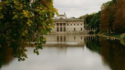 An overview of a palace in the distance with a lake in the foreground
