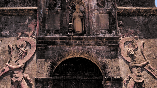 Ornate stone entrance of St Jerome Fort featuring historic carvings and a cross above the gateway.