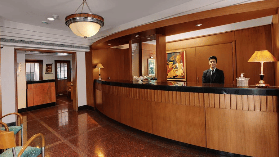 A hotel reception desk with a staff member standing behind the counter | Trance Oakwood Hotel, Pune
