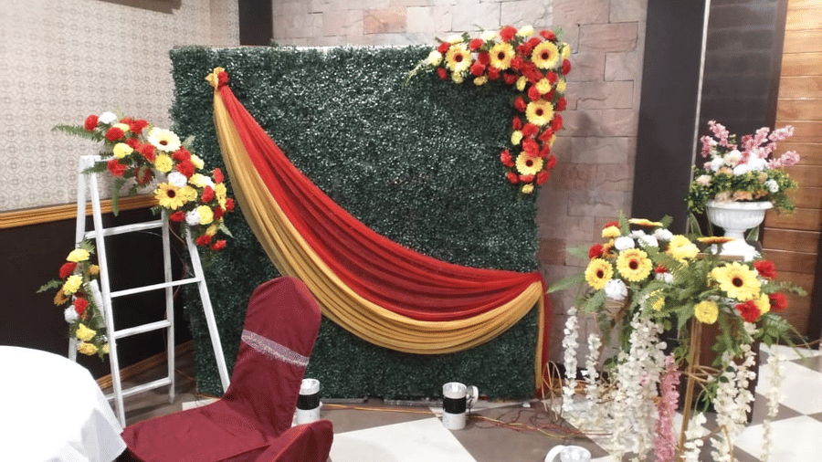 Elegant photo booth setup with green foliage, red drapes, and floral arrangements at Central Courtyard Boutique Hotel.