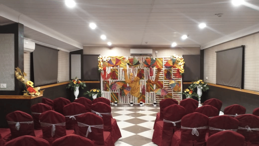  Banquet hall setup with maroon chairs and a well-lit stage for special events at Central Courtyard Boutique Hotel.