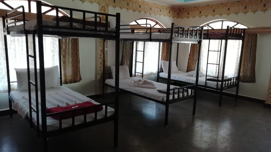 A close-up of bunk beds with neatly made beds and windows with side-pulled curtains at Riverside Inn.