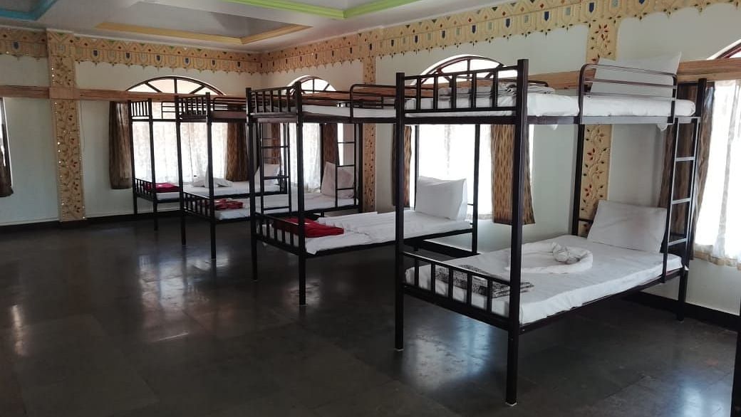 A diagonal view of the dormitory at Riverside Inn with bunk beds side by side and light streaming through the windows.