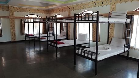 A diagonal view of the dormitory at Riverside Inn with bunk beds side by side and light streaming through the windows.