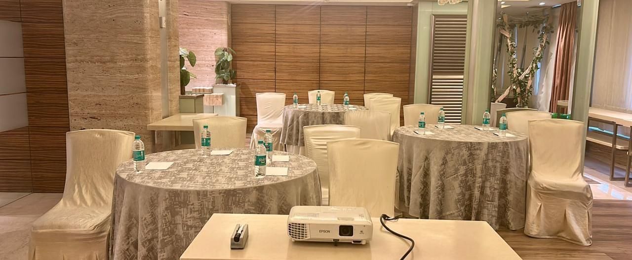 Conference-style setup with covered chairs and a central projector on a table at Mirage Hotel, Mumbai.