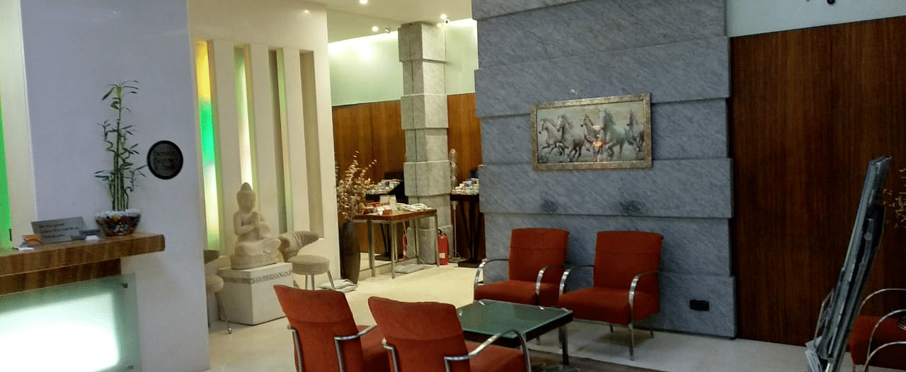 Reception area with a comfortable chairs around a glass table at Regency Hotel, Mumbai.