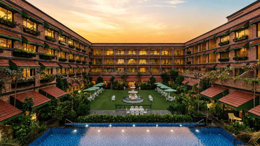 The resort courtyard featuring a central lawn, water fountain, and blue pool at MAYFAIR Bay Resort, Paradeep.