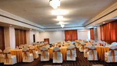 A banquet hall with round tables and chairs covered in cloth at the best resort in Bangalore | Ramanashree California Resort