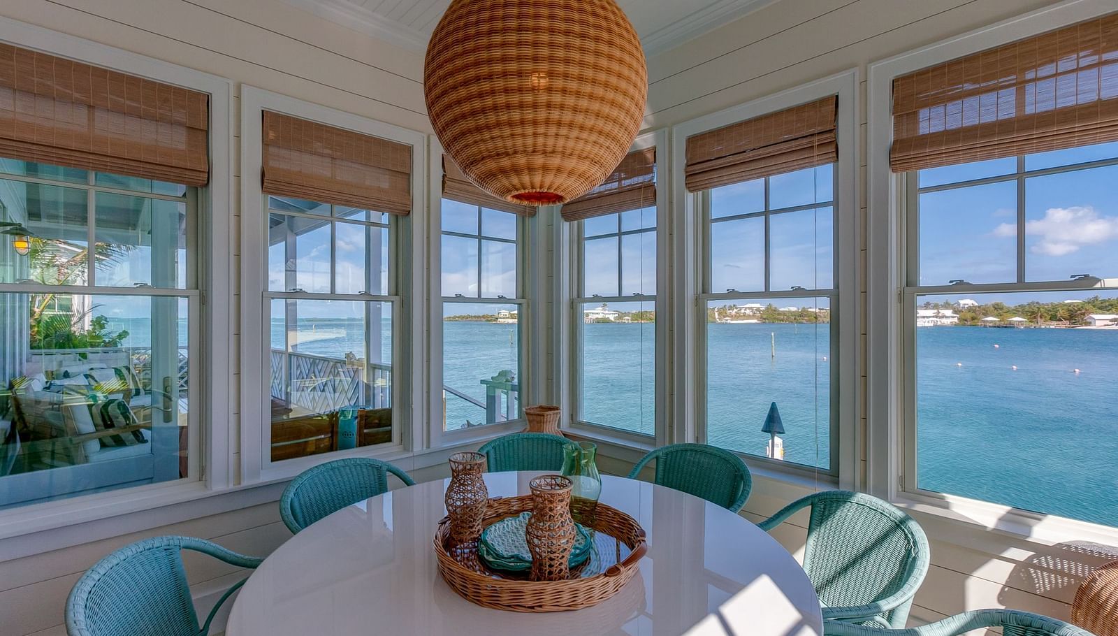 Dining area with a round table, wicker pendant light, and large windows overlooking the water | Abaco Inn