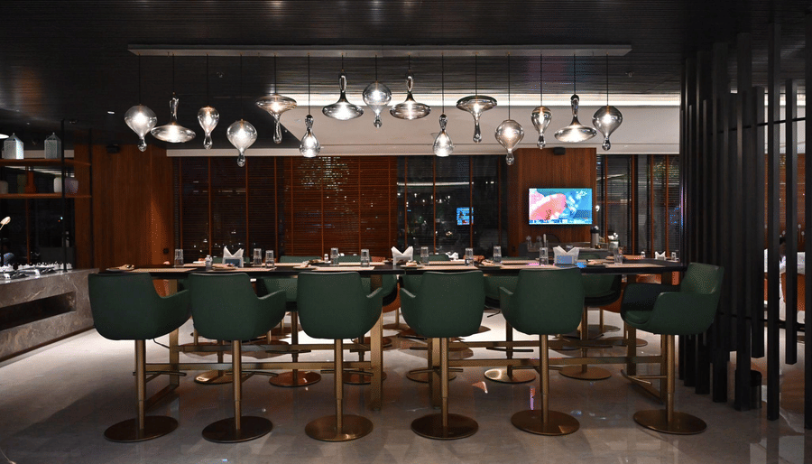 A sleek bar lounge featuring green bar stools and ambient lighting, designed for upscale dining and drinks.