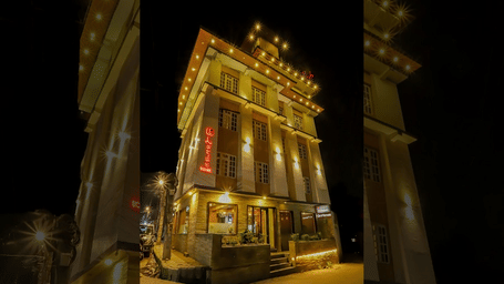 A narrow, tall building lit up at night with streetlights and reflections on the ground.