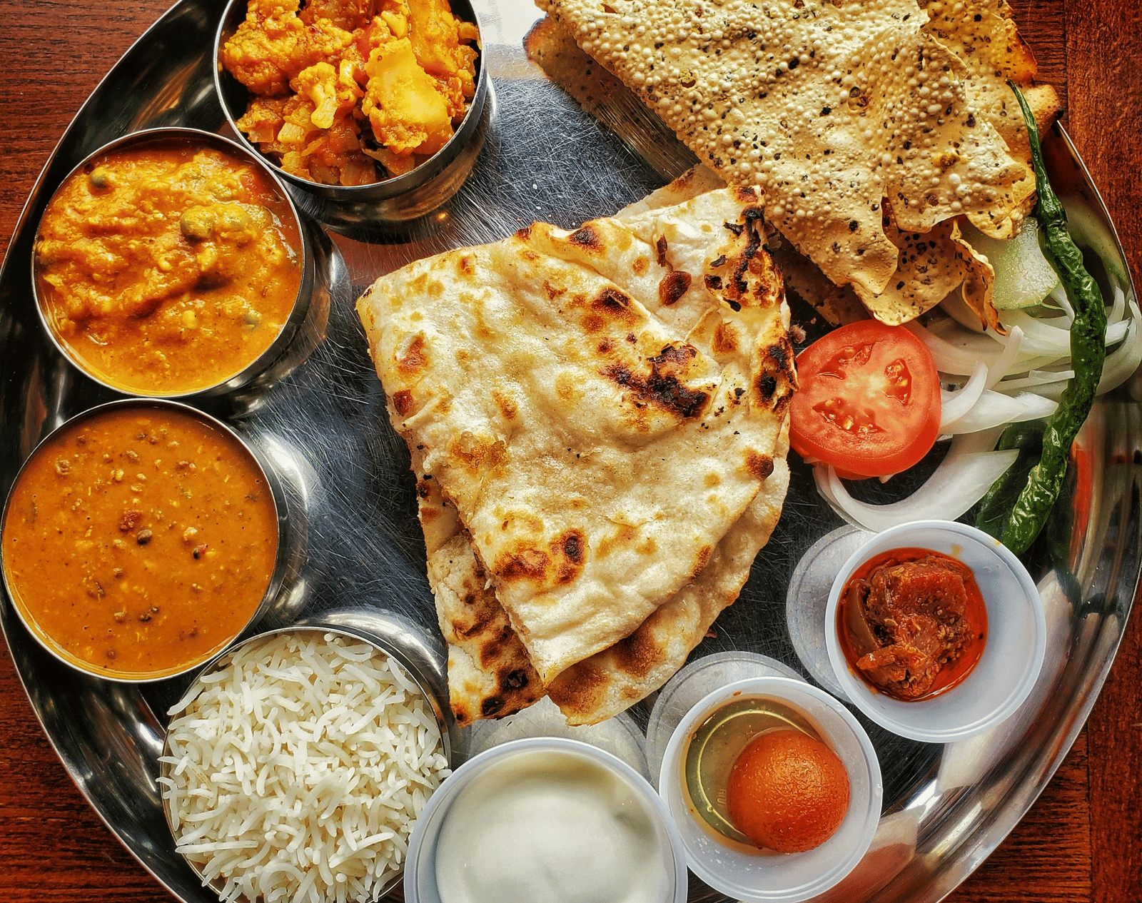 A neatly arranged plate with several Indian delicacies served.