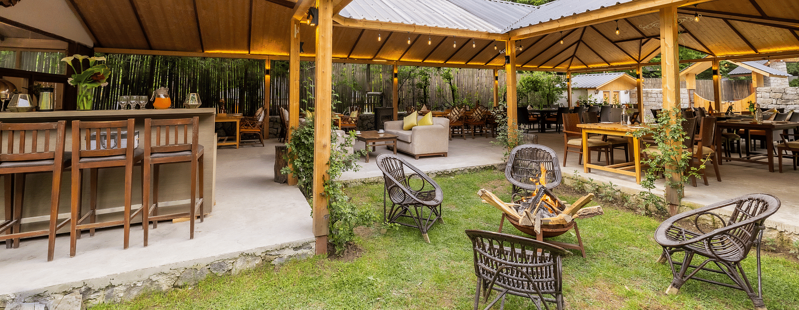 An open dining area with lavish wooden interiors, atttic style roof, wooden chairs and table at Bedzzz Xclusiv Baikunth, Manali