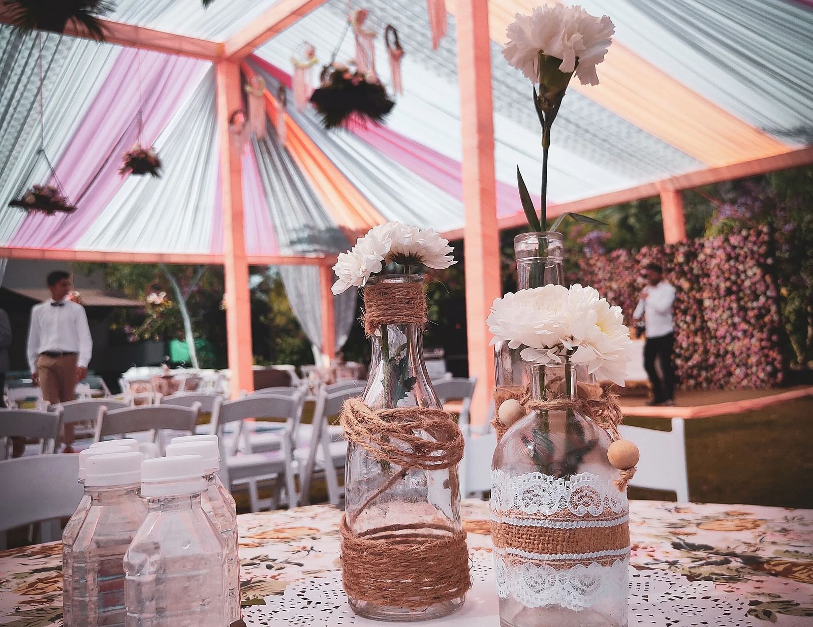 A tent decorated with colourful fabrics, branches, and vases.