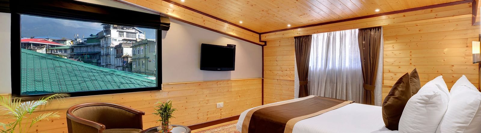 A queen bed opposite a sofa and table in attic family room - Sumitel Shangrila, Deorali