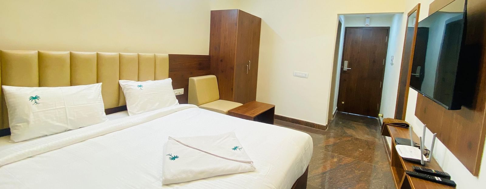 Well-lit deluxe room with plush bedding and stylish wood accents for a restful stay at Hotel Sahara Tree.