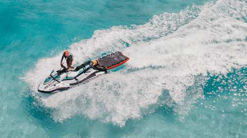An aerial view of a person jet skiing in the turquoise waters during their Corbyn’s Cove Beach Activities