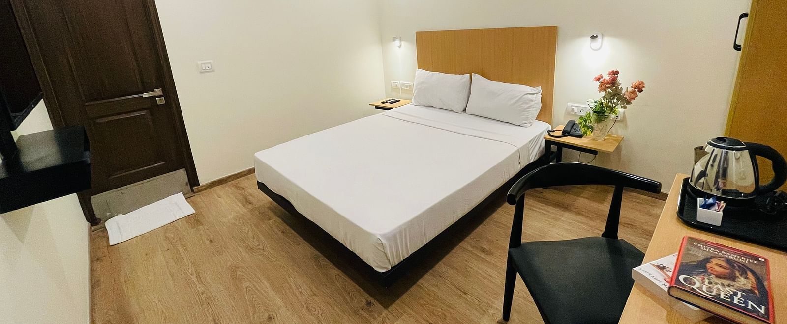 A double bed and a work desk on which a tea and coffee maker is placed at Sanctum Suites Richmond Road, Bangalore