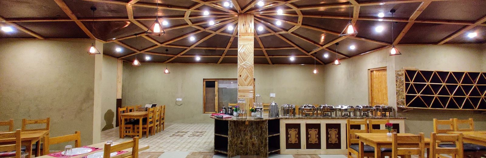 The interior of a dining area with wooden tables and chairs at White Sands Resort, Ladakh.