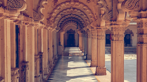 A long, arched corridor with ornate pillars and a domed ceiling, creating a sense of a grand historical palace.