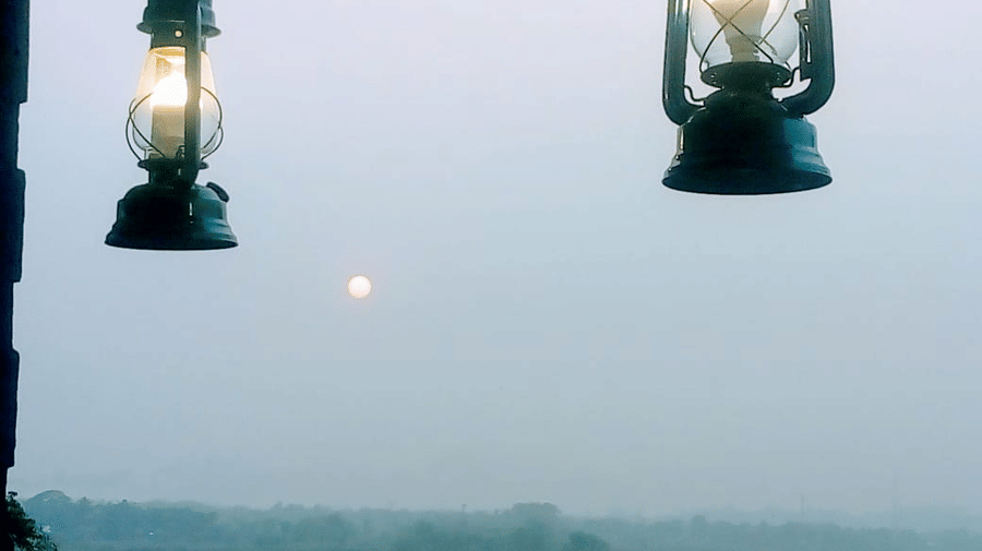The balcony of a room at Lake Side Resort Neermahal, with 2 lamps, and sky in the backdrop.