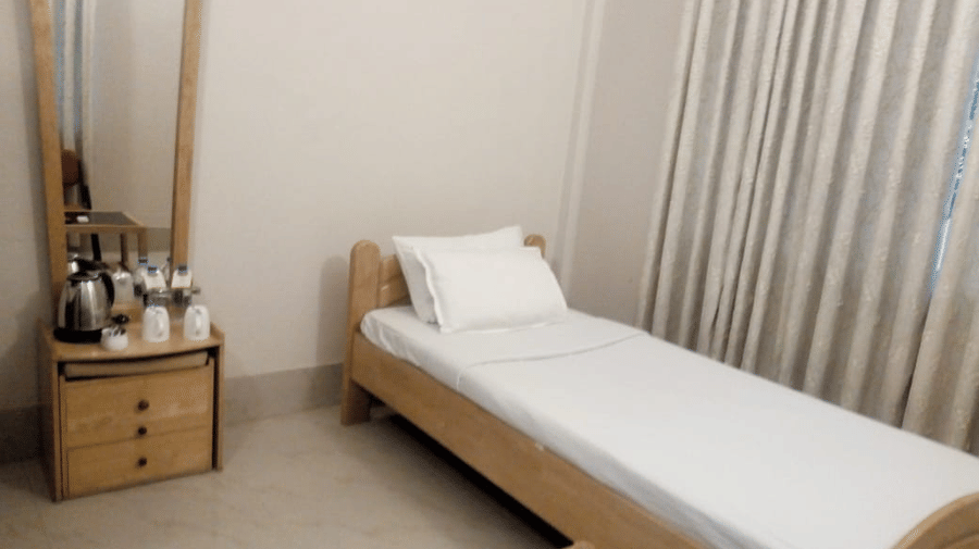A room at Lake Side Resort Neermahal, featuring a single bed, bedspreads, a pillow, and a dressing table.