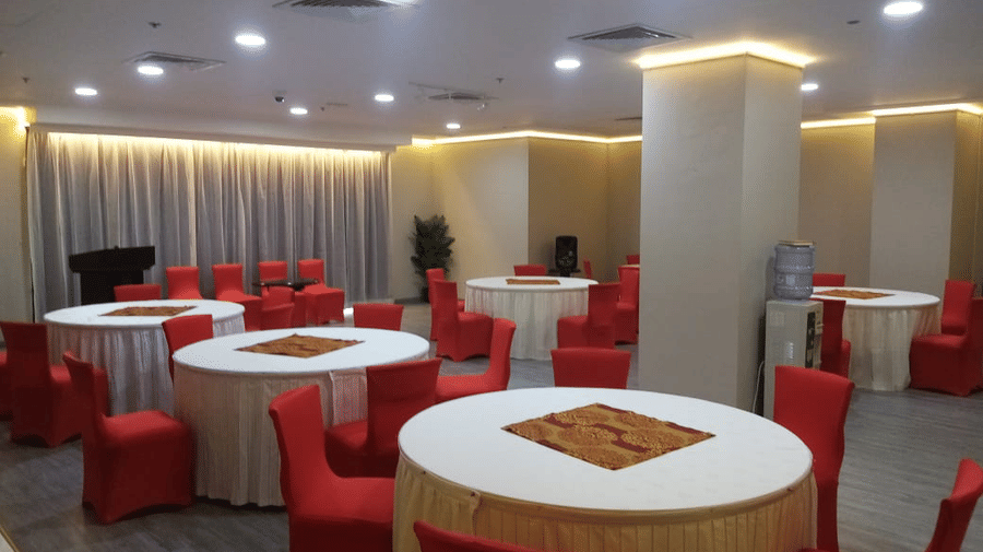 Red chairs surround round dining tables in a carpeted event space featuring recessed lighting and square pillars - Al Manar Grand Hotel Apartment, Bur Dubai