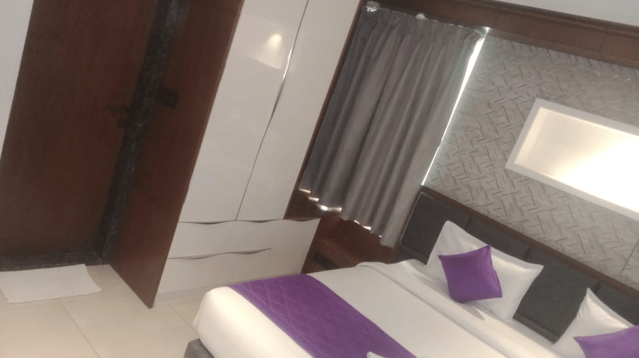 Corner view of the Executive Suite with a modern wardrobe alongside the door to the bathroom placed beside the double bed at SRS Suites, Koramangala.