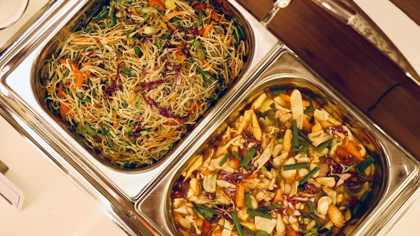Buffet trays filled with stir-fried noodles and mixed vegetables in sauce with vibrant garnish - Jenneys Residency, Coimbatore