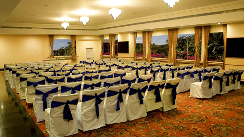 A conference room with rows of chairs covered with cloth at the best resort in Bangalore  | Ramanashree California Resort