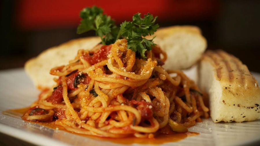 A bowl of pasta with red sauce and bread on a white plate | Altamont Court, Jamaica
