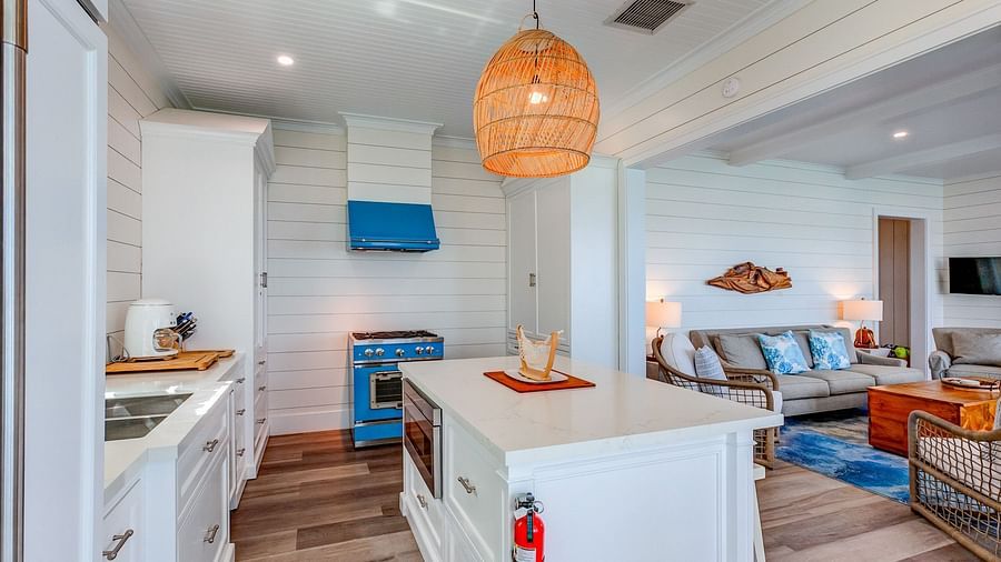 Open kitchen and living area with a white island, blue stove, and wooden accents | Abaco Inn