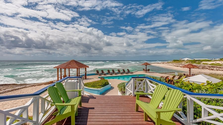 Deck with green chairs and ocean view under a blue sky | Abaco Inn