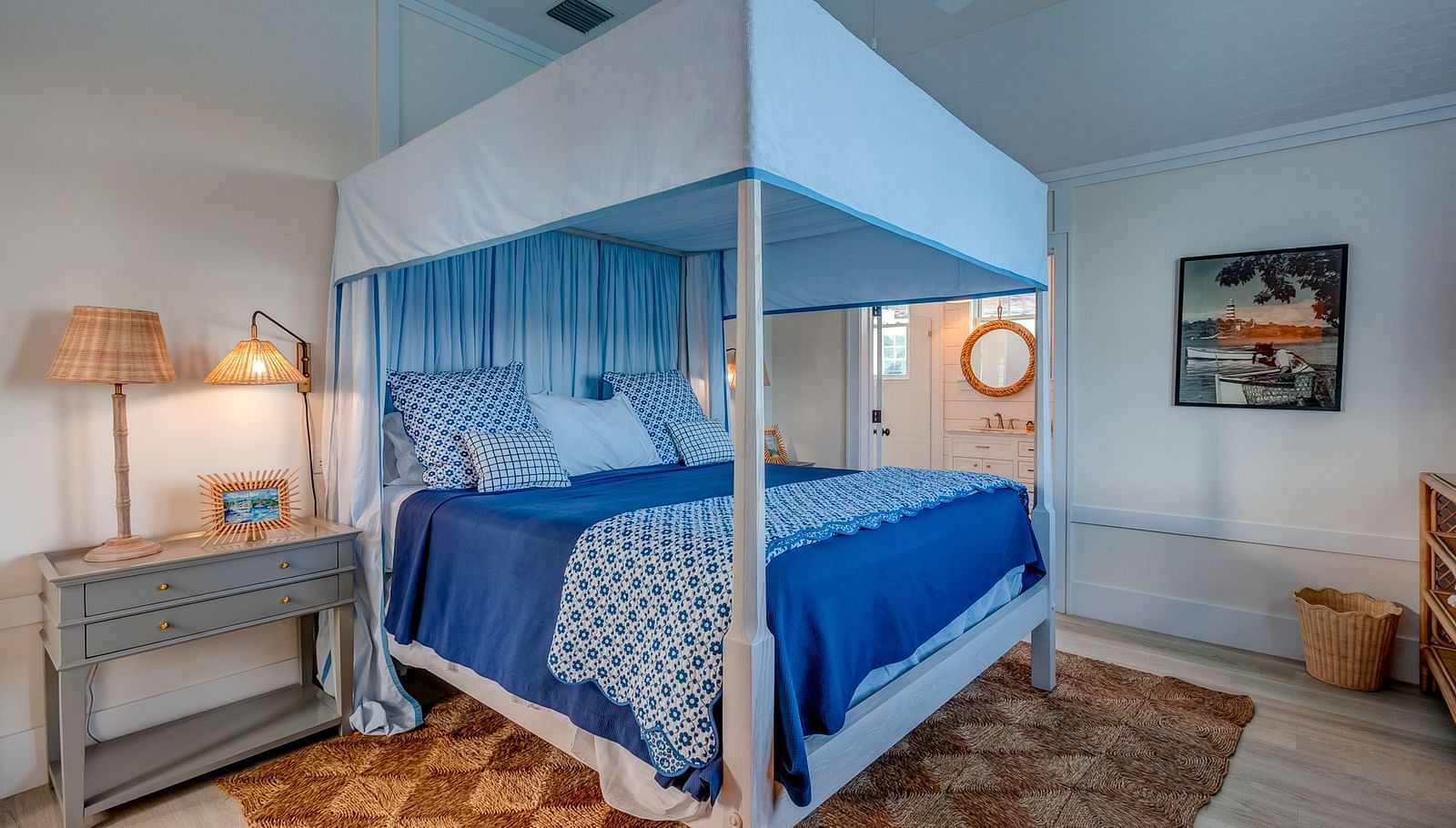 Bedroom with a blue canopy bed, wooden nightstand, and soft lighting | Abaco Inn