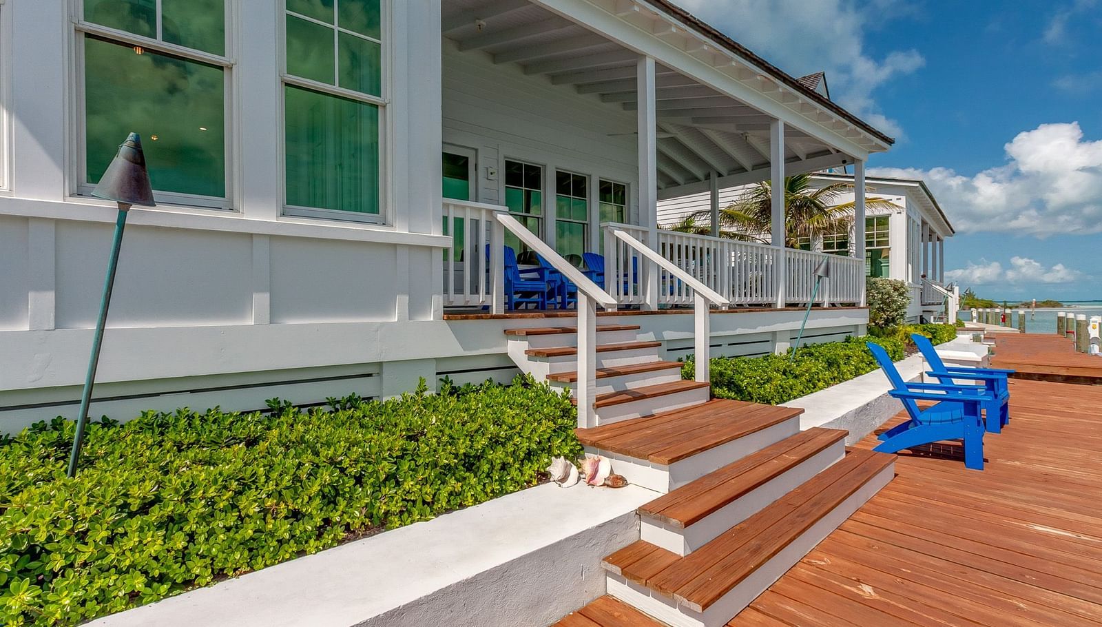 Waterfront deck with blue Adirondack chairs and a view of the calm sea | Abaco Inn