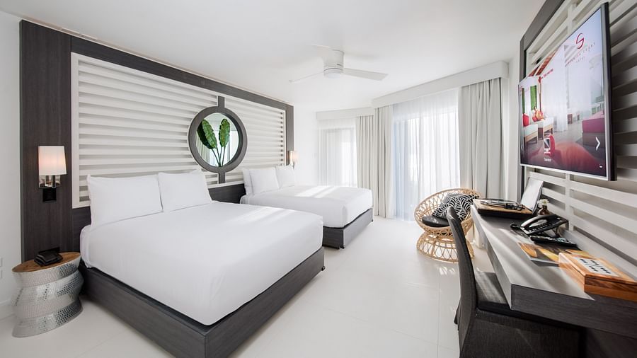 A hotel room with double beds, a wall mounted television and a floor-to-wall ceiling - S Hotel Montego Bay, Jamaica