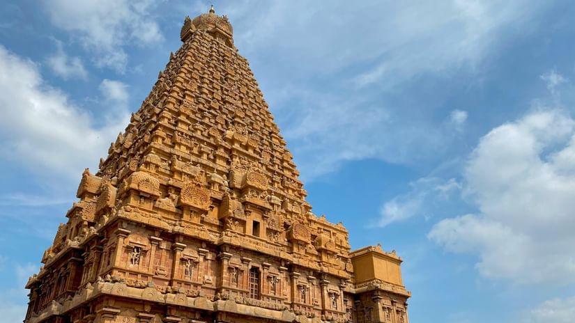 Intricately carved exterior of the Thanjavur temple, seen against the backdrop of a bright blue sky.