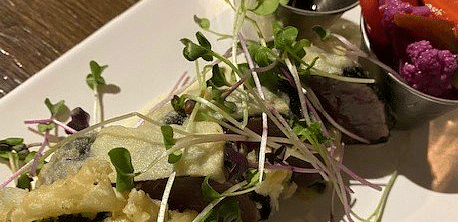 A plate with microgreens, sliced mushrooms, and edible flowers, possibly a salad or garnish.