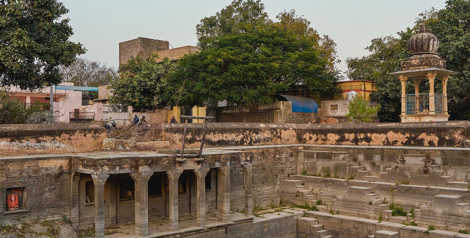 image of a step well surrounded by trees constructed in a typical rajasthani architecture