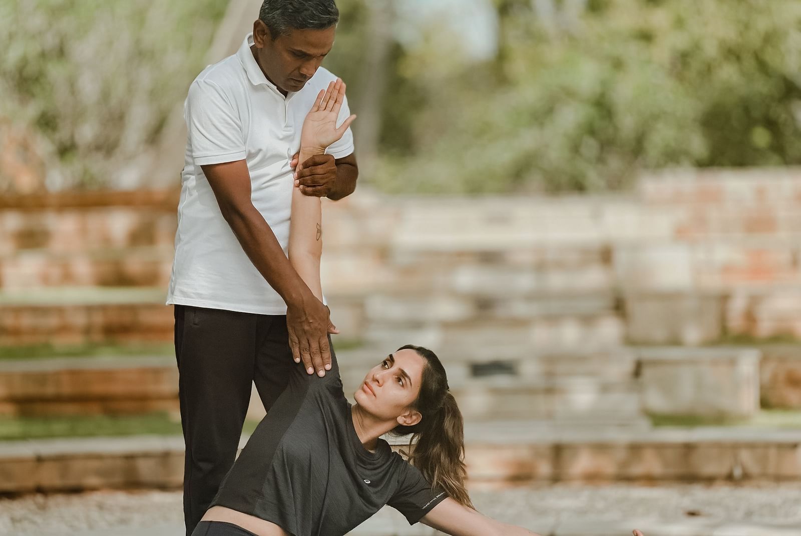 People doing yoga poses outdoors, stone steps, trees in background - Shreyas Retreat