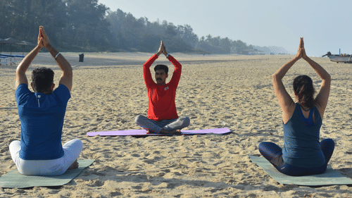 People sitting on the beach and practising yoga