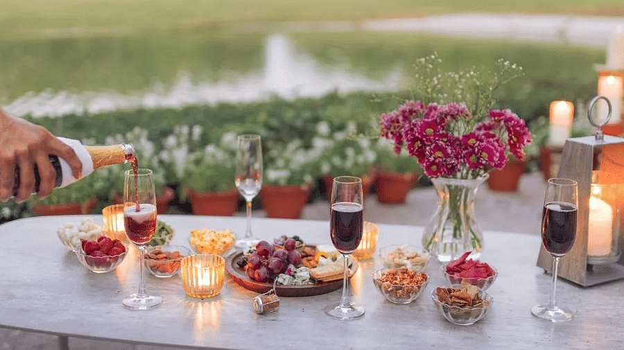 Dessert table setup near a lake with candles, pink flowers, and an assortment of sweets in glassware at Karma Chalets.