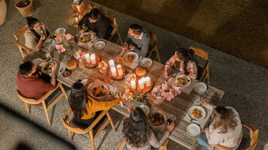 Aerial view of people dining together around a candle-lit dinner table with food and drinks at Karma Chalets.